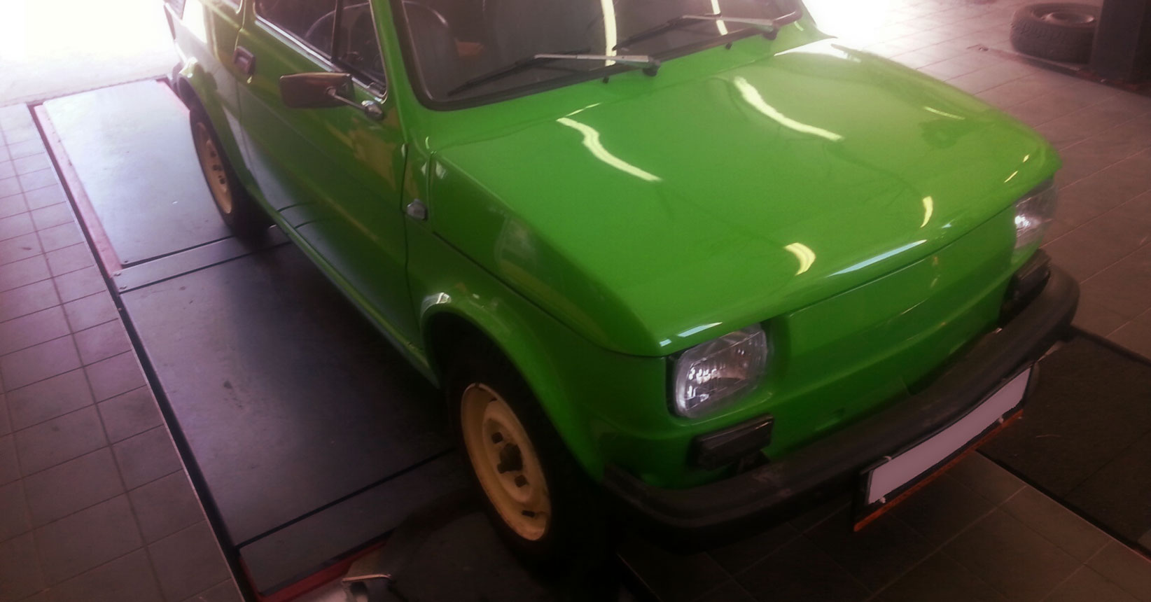 zelený Fiat 126 P uvnitř pneuservisu